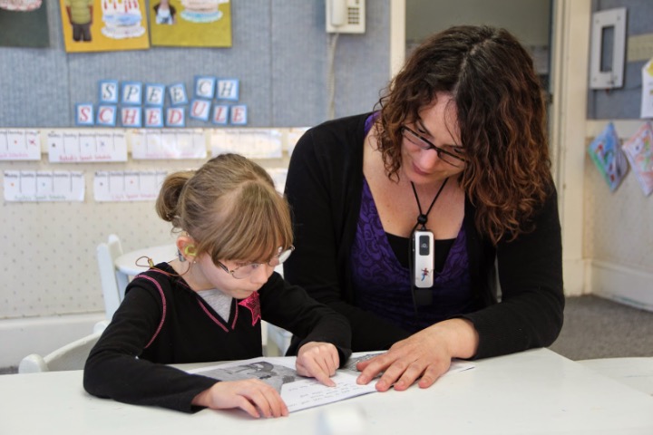 A student and a teacher looking at a book together.