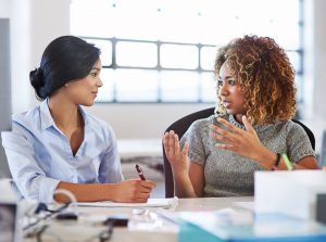 Two female adults at a table in discussion