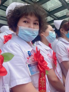 Author, wearing face mask, surrounded by nurses.
