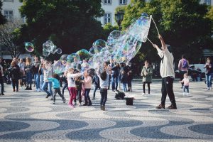 Many children and adults playing together with large bubbles.