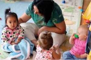 Caregiver sitting with three infants