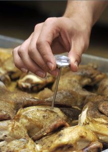 Inserting a meat thermometer into a chicken thigh