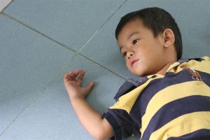 Young boy laying down on the floor.