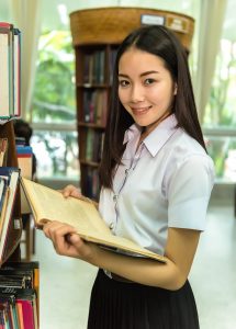 student holding a book in a library