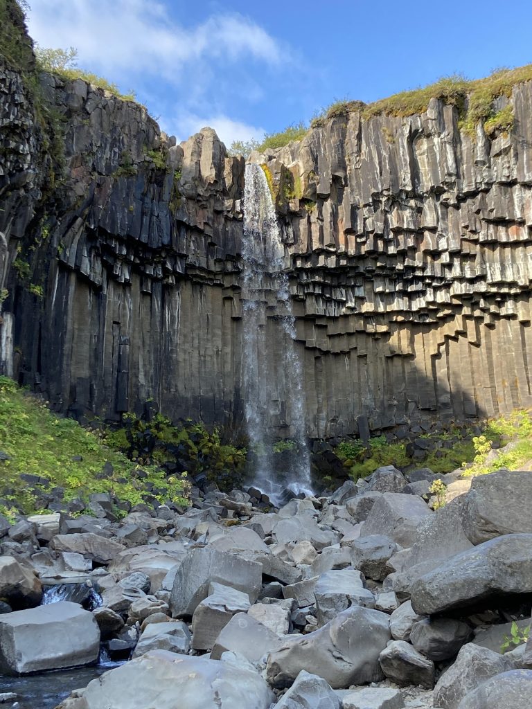 Waterfall over a cliff face of vertical hexagonal columns of cooled basaltic lava.