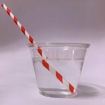 photograph of a straw sticking out of a glass of water. The straw looks like it is bent at the surface of the water with a distinctly different angle on the portion out of the water versus the portion that is in the water.