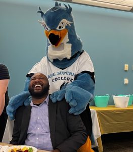 Laughing person with LSC mascot behind them